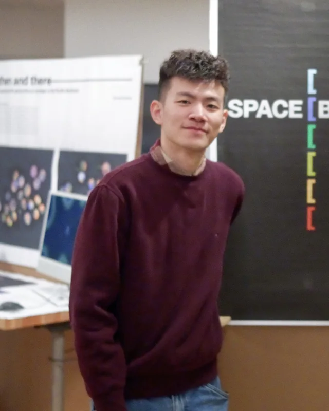 Zhuoqi Liu on the opening day of the MFA thesis exhibition, standing beside the project panels