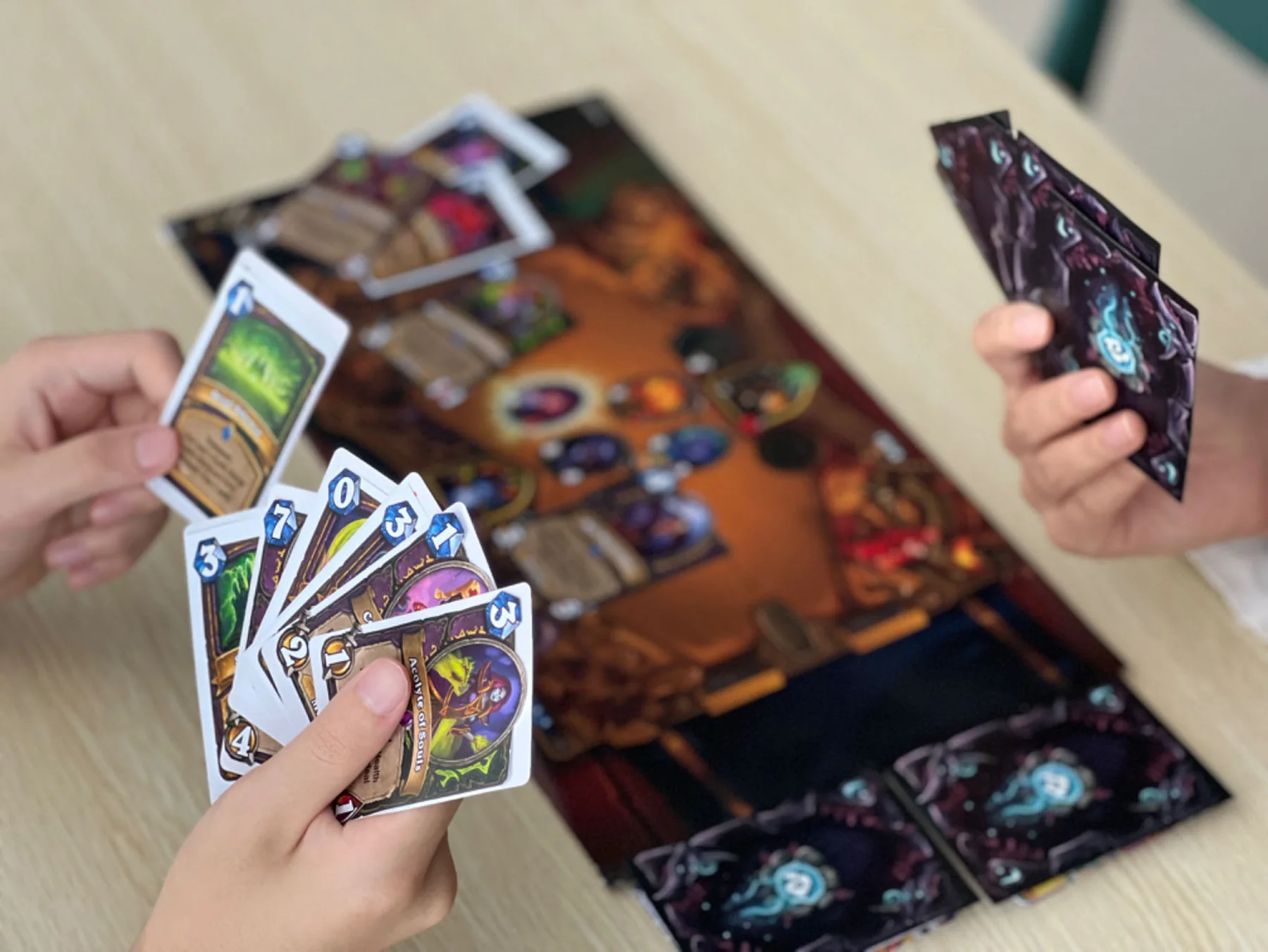 Two players holding printed cards over a paper game board.